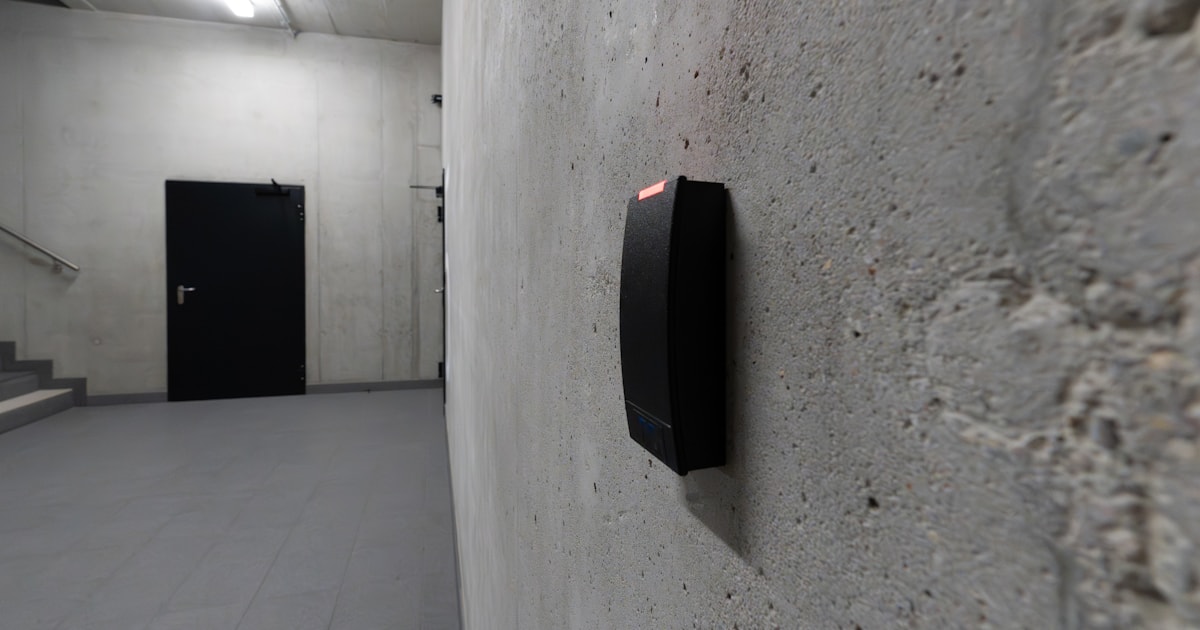 Electronic card reader mounted beside a closed door in an empty concrete stairwell