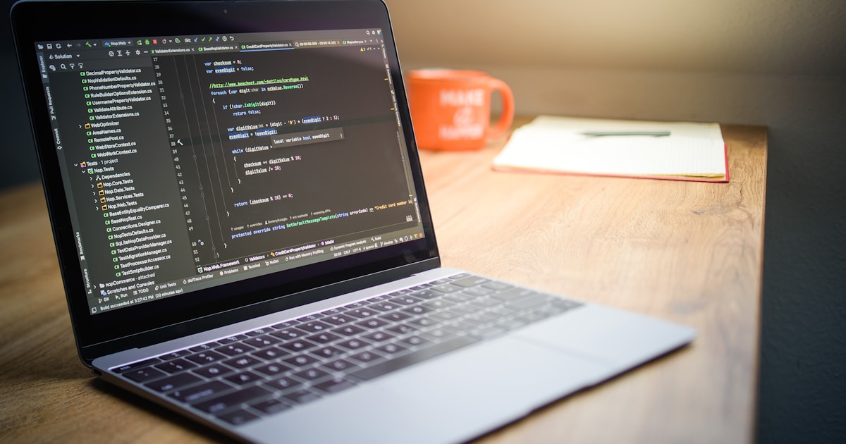 Laptop screen displaying JavaScript code beside a coffee mug