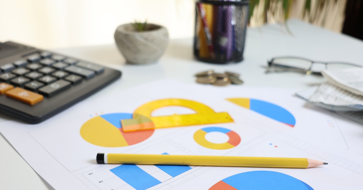Printed charts, calculator, pencil, and office supplies arranged on a desk